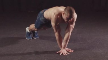 Kot şortlu genç adam kolları ve omuzları için dayanıklılık egzersizi yapıyor.