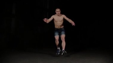 Genç bir sporcu koşuyor ve siyah stüdyoda takla atıyor.