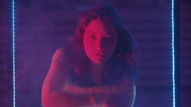 Gülümseyen kadın duman ve neon ışıkta dans eder.