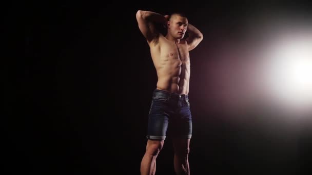 Молодий спортивний чоловік зігрівається в чорній студії — стокове відео