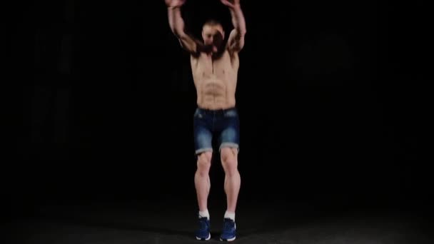 Молодий спортивний чоловік піднімається і робить фліп в чорній студії — стокове відео