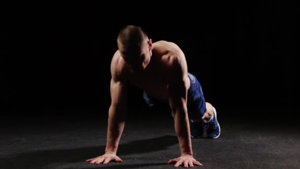 Ein junger Sportler wärmt seinen ganzen Körper mit Liegestützen auf und rennt auf der Stelle — Stockvideo