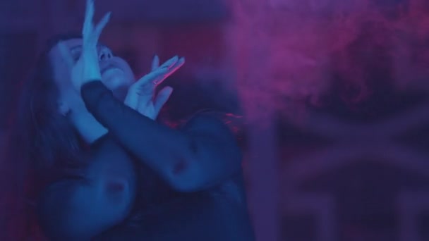 Приваблива жінка танцює в диму і неоновому освітленні — стокове відео