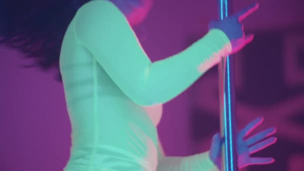 Attractive woman dancing by the pole in neon lighting in the club — Stock Video