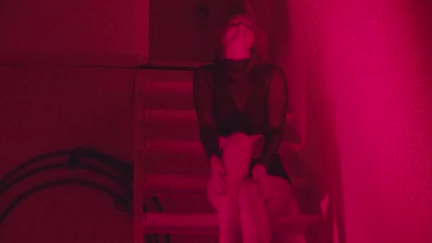 Sexy Frau tanzt im Rotlicht auf Treppe im Club — Stockvideo