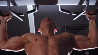 Formda bir adam spor salonunda barfiks çekiyor.