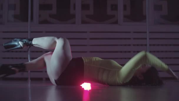 Attraktive Frau tanzt sexy auf dem Boden mit einer roten Lampe hinter sich — Stockvideo