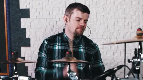 Бородатий чоловік в навушниках б'є по барабанах — стокове відео