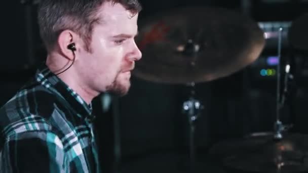 Молодой музыкант в наушниках потеет и бьет в барабаны в студии звукозаписи — стоковое видео