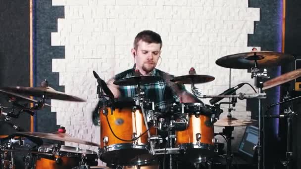 Бородатий чоловік в навушниках потрапляє на барабани в студії звукозапису — стокове відео
