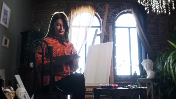 Uma jovem mulher bonita em oficina de arte misturando tons em uma paleta — Vídeo de Stock
