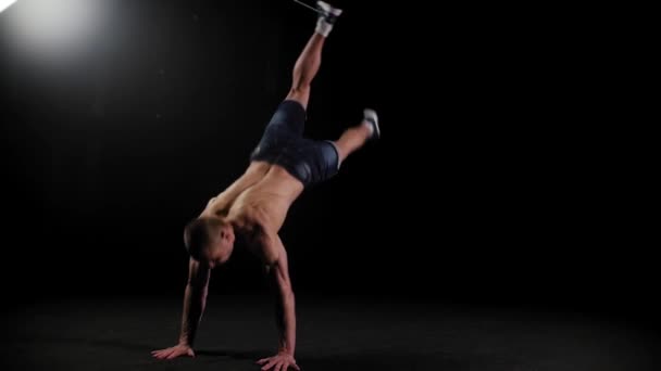 Junger gepumpter Mann macht akrobatische Kunststücke in der dunklen Arena — Stockvideo