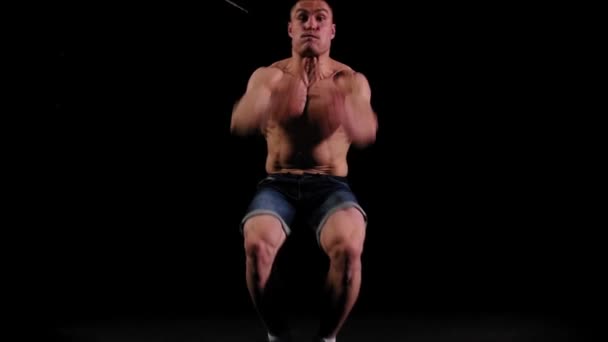Молодий накачаний чоловік робить зворотні перевертання і штовхає в темну арену — стокове відео