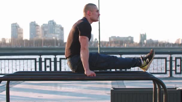 Sportlicher Mann lehnt mit den Händen auf dem Sportplatz an der Stange — Stockvideo