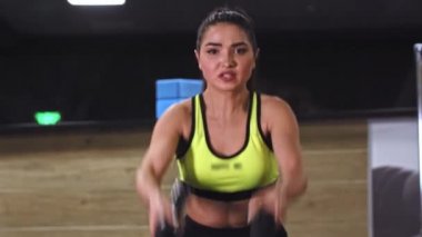 Spor salonunda ip egzersizi yapan genç bir kadın.