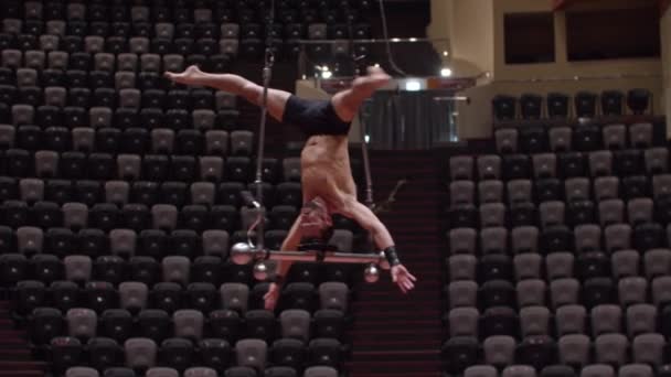 Sirk arenasındaki performans inşaatında baş aşağı asılı akrobatik bir adam. — Stok video