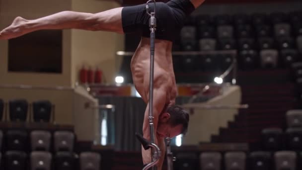 Hombre barbudo acrobático de pie sobre las manos boca abajo en la construcción de rendimiento en la arena del circo — Vídeo de stock