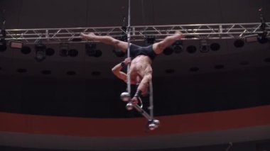 Sirk arenasında akrobatik adam eğitimi. Performans inşaatında elleri olmadan baş aşağı duruyor.