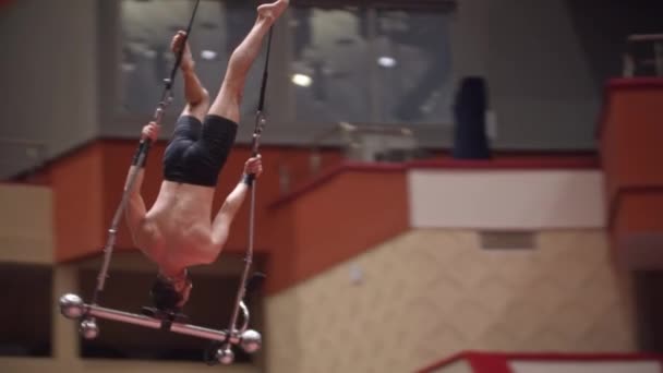 Hombre acrobático balanceándose sobre su cabeza en la oscilante construcción de rendimiento rotatorio en la arena del circo — Vídeos de Stock