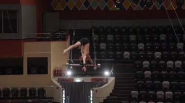Sirk arenasında performans inşaatında baş aşağı duran akrobatik adam.