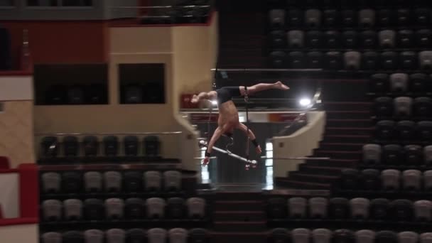 Акробатичний чоловік летить навколо догори ногами на виступі на висоті на цирковій арені — стокове відео