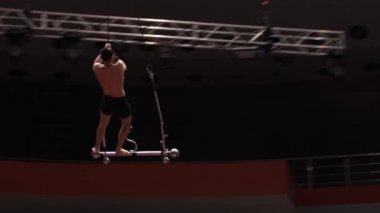 Akrobatik tişörtsüz bir adam sirk arenasında gösteri yapıyor.