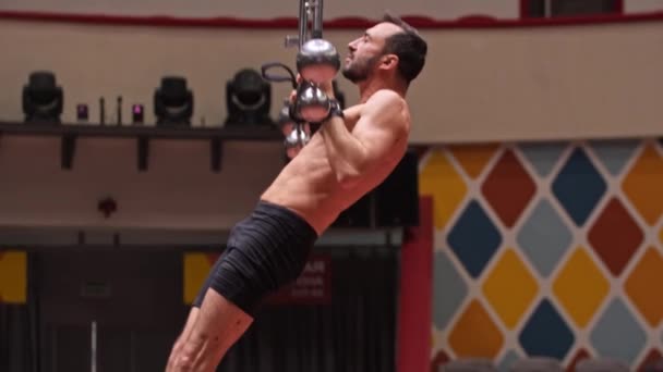 Акробатический мужчина без рубашки тренирует руки на цирковой арене — стоковое видео