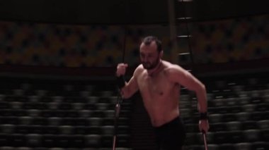 Boş bir sirkte antrenman. Havadaki metal yapımında ayakta duran ve dengede duran bir adam.