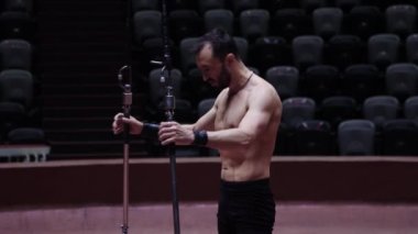 Sirkte antrenman yapıyor. Akrobatik bir adam boynunu ısıtıyor ve gösteriye havada başlıyor.