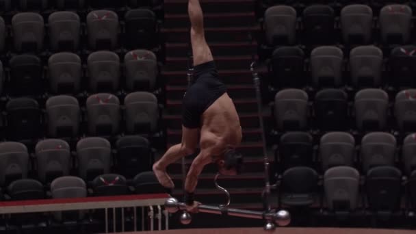 Treinamento em circo - um homem acrobático descansa em sua boca sem mãos e pernas na construção para o show — Vídeo de Stock