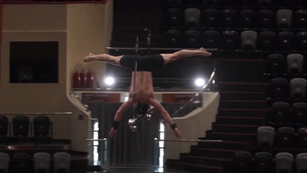 Trénink v cirkuse - akrobatický muž předvádějící se na létající konstrukci - stojící vzhůru nohama bez rukou a nohou — Stock video