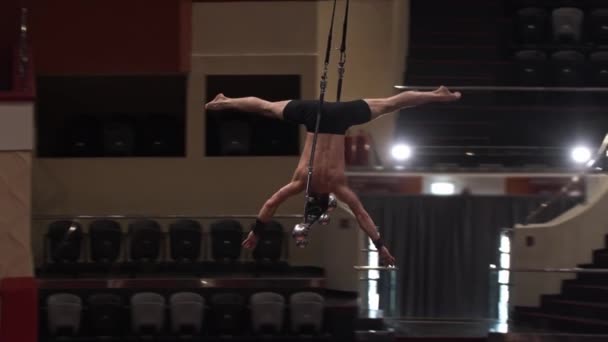 Training in circus - een acrobatische man doet een show over de vliegende constructie - ondersteboven staan zonder de steun — Stockvideo