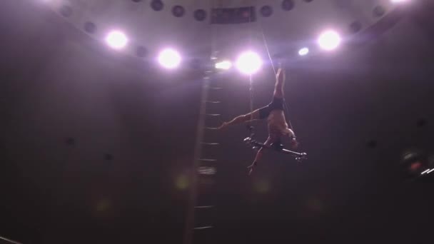 Un acrobate faisant une représentation au bar volant au cirque dans des lumières vives — Video