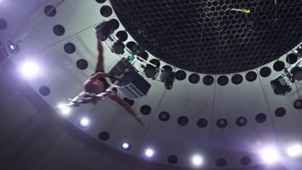 Un bărbat acrobatic antrenându-și performanța pe bara de zbor de la circ în lumini strălucitoare — Videoclip de stoc