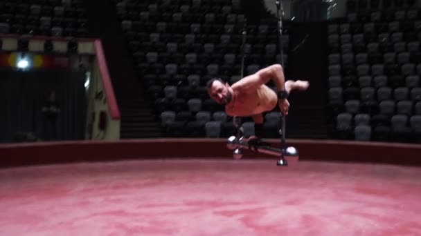 Um homem acrobático treinando sua performance no bar voador no circo em luzes brilhantes subindo no bar no ar — Vídeo de Stock