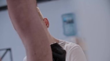 Genç bir sanatçı, kuafördeki müşterisinin bacağına dövme çiziyor.