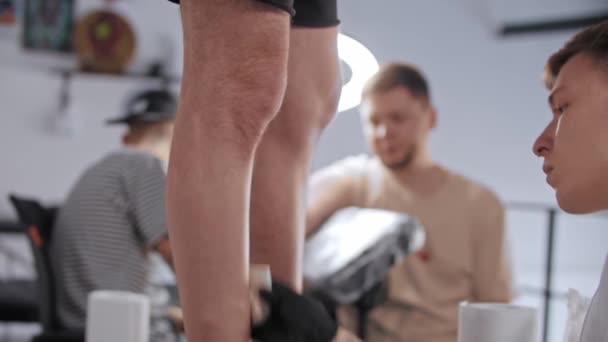 Jovem rapa a perna de seu cliente para tatuagem — Vídeo de Stock