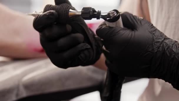 Dövmeci çalışmadan önce dövme makinesi yapıyor. — Stok video