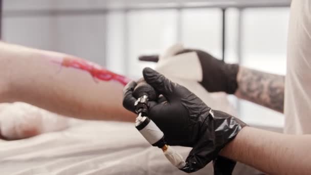 Татуювання художник починає татуювання на нозі свого клієнта — стокове відео