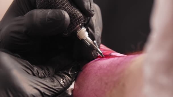 Salone del tatuaggio - giovane uomo che fa un contorno tatuaggio sulla gamba del suo cliente — Video Stock