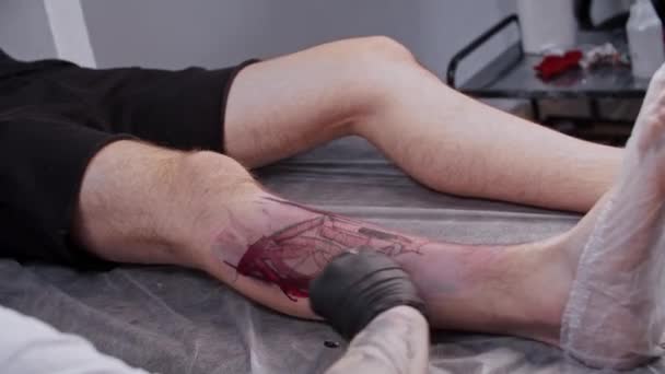 Un uomo che fa una sessione di tatuaggio - facendo un tatuaggio sulla gamba — Video Stock