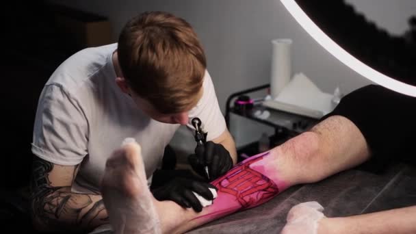 Salão de tatuagem - jovem mestre tatuando e preenchendo o esboço com tinta preta — Vídeo de Stock