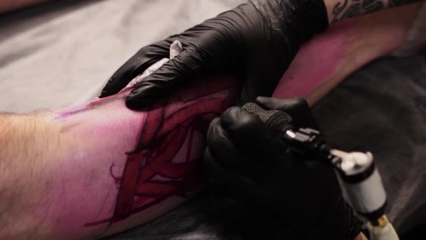 Татуювання салону клієнт лежить на дивані і отримує татуювання великих літер на нозі — стокове відео