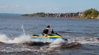 KAZAN, RUSSIA 21-05-21: a man riding yellow jet ski in circles on the water