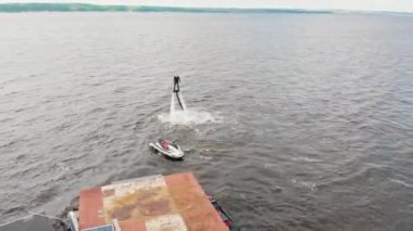 KAZAN, RUSSIA 21-05-21: a person flying up over the water near the floating house and a jet ski - aerial view