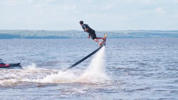 KAZAN, RUSSIA 21-05-21: Jongeman doet oefeningen met een flyboard met een jetski in de buurt van — Stockvideo