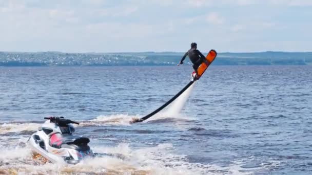 KAZAN, RUSSIA 21-05-21: Jongeman doet oefeningen met een flyboard over de rivier met een jetski in de buurt — Stockvideo