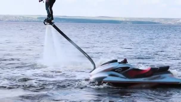 Deux hommes apprenant à utiliser des planches volantes sur la rivière avec un jet ski à proximité — Video
