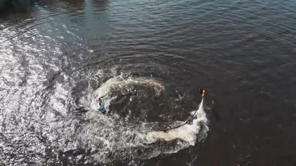 Чоловік літає над водою та інший чоловік катається на реактивних лижах по колу - вигляд з повітря — стокове відео