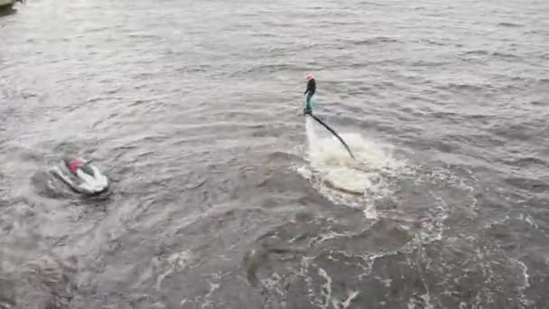 A man flying on the flyboard and other man riding jet ski in circles - aerial view — Stock Video